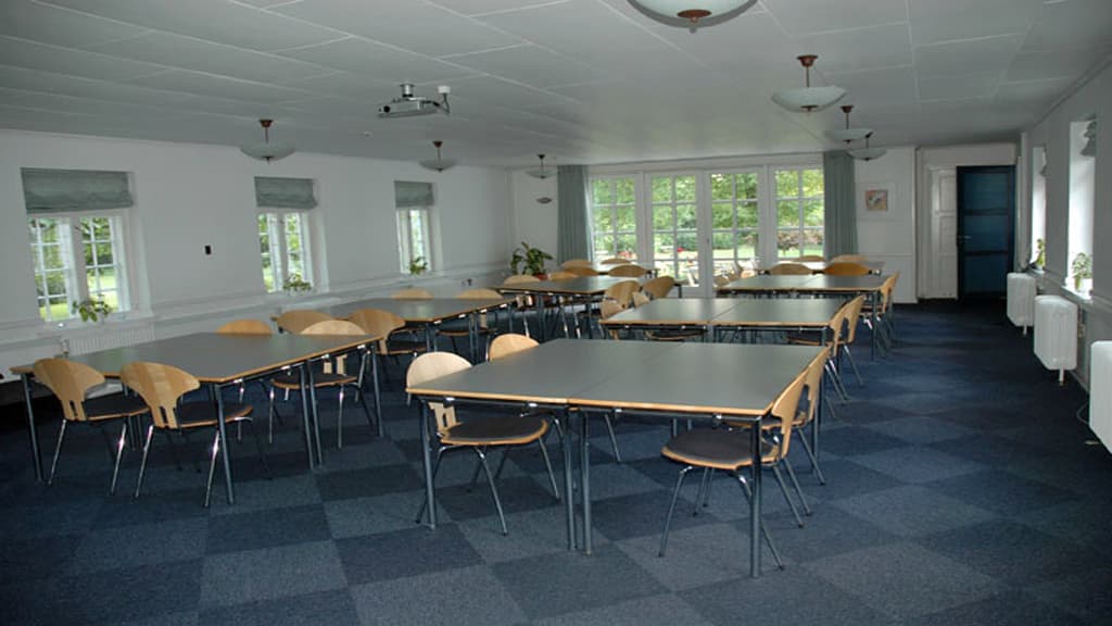 Brandbjerg Manor room with tables and chairs on a dark gray carpet.